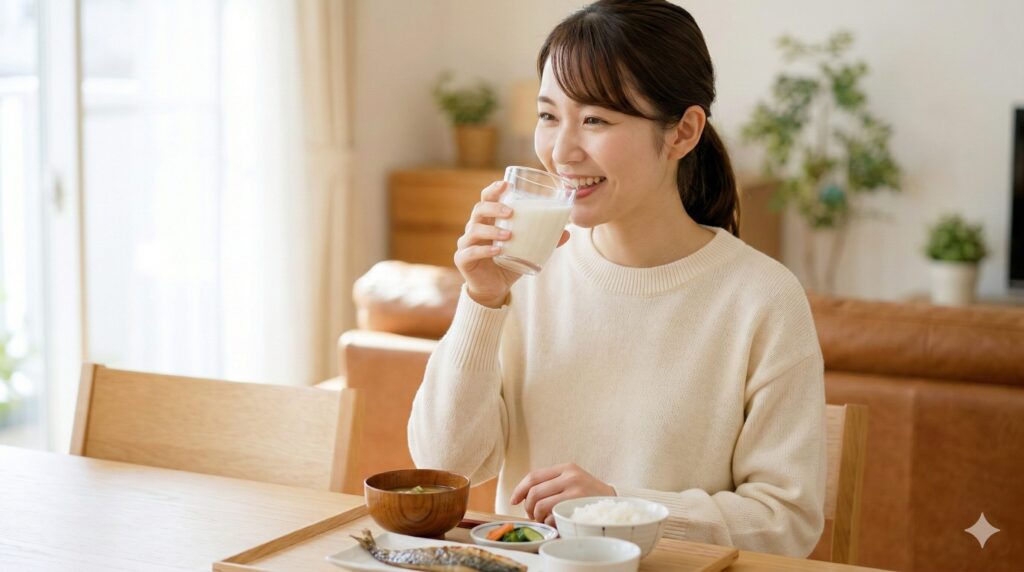 日本の自宅で、笑顔で青と白のボトル飲料(L-92乳酸菌関連商品)を飲む日本人女性。朝食のテーブルに置かれている。